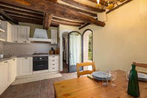 une cuisine avec des placards blancs et une table avec une salle à manger dans l'établissement Casale Mulin Bianco, à Monteriggioni