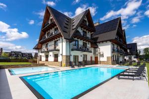 a house with a swimming pool in front of a house at Hotel Bystra in Białka Tatrzanska