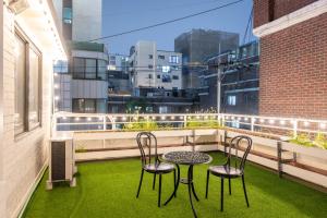 a balcony with two chairs and a table on the grass at Le Cocon Seoul in Seoul