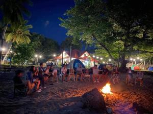 un grupo de personas sentadas alrededor de un fuego en la playa por la noche en Lamec Beach Resort, en Sibulan