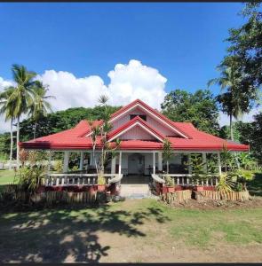 una casa con techo rojo y palmeras en Lamec Beach Resort, en Sibulan