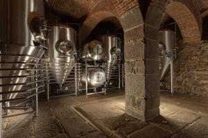 une rangée de réservoirs en argent dans un bâtiment en briques dans l'établissement Pivovar Rožmberk, à Rožmberk nad Vltavou