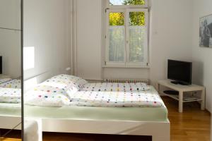 a white bedroom with a bed and a television at Ferienwohnung Baden Baden in Baden-Baden