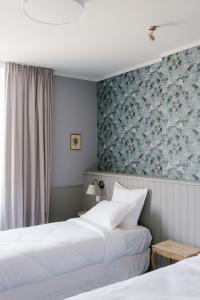 two beds in a hotel room with blue wallpaper at La Maison d’Hôtes in Silly