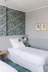 a bedroom with two beds and a floral wallpaper at La Maison d’Hôtes in Silly