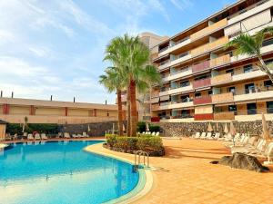 un hôtel avec une piscine et des palmiers dans l'établissement Cosy well located apartment, à Puerto de Santiago