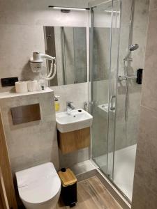 a bathroom with a shower and a toilet and a sink at Hotel Gromada Łomża in Łomża