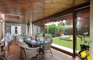 jadalnia ze stołem, krzesłami i oknami w obiekcie Villetta Golf Holidays w mieście Soiano del Lago