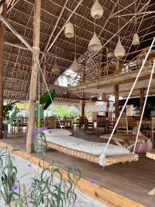 ein großes Bett in einem Pavillon mit Tischen und Stühlen in der Unterkunft Boutique Villa Unaweza in Matemwe