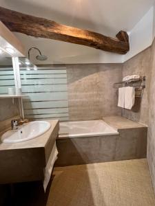 a bathroom with a tub and a sink at Hôtel Le France in Aubusson