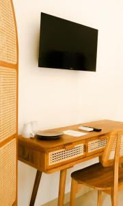 einen Holztisch mit einem TV an der Wand in der Unterkunft Shortcut Breeze Guest House in Canggu