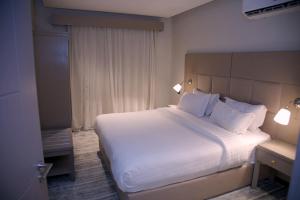 a bedroom with a large bed with white sheets and pillows at Sharz Hotel in Buraydah