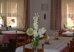 Ein Esszimmer mit Tischen, auf denen weiße Blumen in einer Vase stehen in der Unterkunft Hotel Garni Christin in Auer