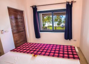 a bedroom with a checkered bed with a window at Pingwe Beach Apartments in Pingwe