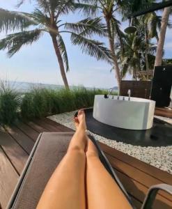 a person laying on a bench next to a bath tub at Villa Mandi in Ban Thong Phlu