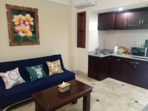 a living room with a blue couch and a kitchen at Kun's Stay Private Apartments in Seminyak