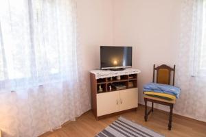 uma sala de estar com uma televisão e uma cadeira em Apartmani Nedjeljko em Čunski