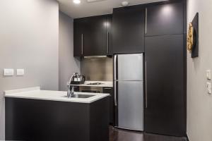 a kitchen with black cabinets and a stainless steel refrigerator at Chatrium Hotel Riverside Bangkok in Bangkok