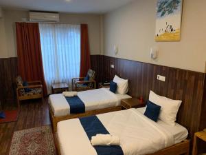 um quarto de hotel com duas camas e uma janela em Khamsum Inn em Thimphu