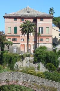 Un gran edificio rosa en una colina con una palmera. en Hotel Villa Bonera, en Génova