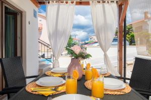 a dining table with a vase of flowers and orange juice at Apartment Dida i Mara in Malinska