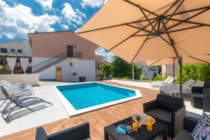 a villa with a swimming pool and an umbrella at Apartment Dida i Mara in Malinska