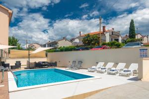 a swimming pool with chairs and a house at Apartment Dida i Mara in Malinska
