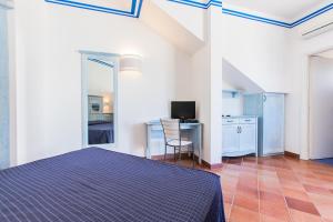 um quarto com uma cama e uma secretária com uma televisão em Resort Cala La Luna em Favignana