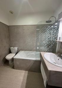 y baño con bañera, aseo y lavamanos. en Hôtel Le France en Aubusson