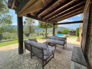 a patio with two benches and a pool at Masia with pool and beautiful views near Girona in Girona