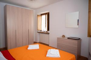 1 dormitorio con 1 cama naranja y 2 toallas en alloggio del Viandante, en Montefiascone
