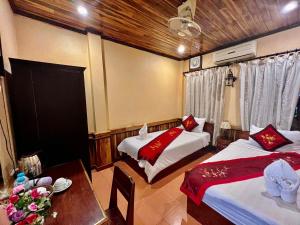 a hotel room with two beds and a table and a table sidx sidx at Nocknoy Lanexang Guest House in Luang Prabang