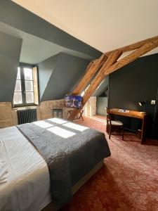 a bedroom with a bed and a desk in a room at Hôtel Le France in Aubusson