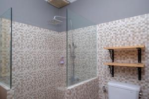 a bathroom with a glass shower with a toilet at Urbanview Hotel Syariah Wisnugraha by RedDoorz in Yogyakarta