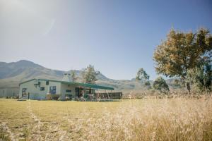 a house in a field with mountains in the background at Farm stay near Greyton, Western Cottage. in Riviersonderend