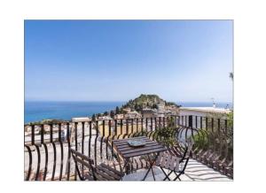 a table and chairs on a balcony overlooking the ocean at PHS Panoramic House Suite in Taormina