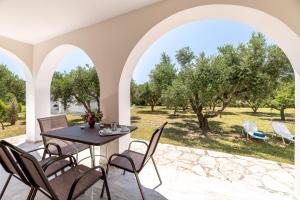 un patio con mesa, sillas y árboles en Lenna's Villas Zante, en Vasilikos