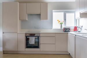 a white kitchen with white cabinets and an oven at Beautiful New 2 Bed Flat - 5 August House in London