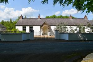 una casa blanca con una puerta y una valla en Luxury Croft Templepatrick Near Airport Rabbit and Hilton hotel en Templepatrick