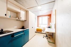 a kitchen with blue cabinets and a bed in the background at Chillout Dorm Cracow by BookingHost in Krakow +30 photos