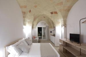 a bedroom with a large white bed and a tv at Carrubia in Nardò