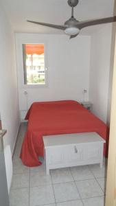biała sypialnia z czerwonym łóżkiem i oknem w obiekcie Agréable T3, Bormes Les Mimosas w mieście Bormes-les-Mimosas