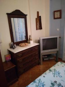 a bedroom with a television and a dresser with a mirror at Villa Gerakina in Gerakini