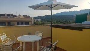 a table and chairs on a roof with an umbrella at Apartaments Las Carolinas in Sant Carles de la Ràpita