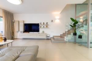 a living room with a couch and a staircase at O&O Group - Prestigious Beachfront Villa W Private Pool in Rishon LeẔiyyon