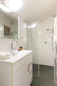 La salle de bains blanche est pourvue d'un lavabo et d'une douche. dans l'établissement O&O Group - Prestigious Beachfront Villa W Private Pool, à Rishon LeẔiyyon
