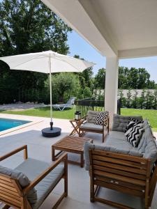 um pátio com cadeiras e um guarda-sol ao lado de uma piscina em Villa Destiny Nedescina, Istrien, Kroatien em Nedeščina