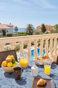 una mesa con comida y zumo de naranja en el balcón en Precioso aprtamento en Rocas Doradas frente al mar en L'Ametlla de Mar