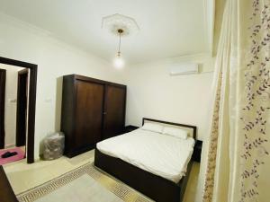 a small bedroom with a bed and a wooden cabinet at شقه مفروشة الجبيهه in Amman