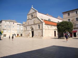 an old stone church with people walking in a courtyard at Budget Apartments Batkoski Pag in Pag